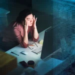 Shot of a young programmer working on computer code at night and looking stressed