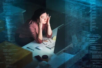 Shot of a young programmer working on computer code at night and looking stressed