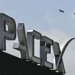 US billionaire businessman and pilot Jared Isaacman flies in formation aboard a fighter jet over the SpaceX sign, close to the Starship spacecraft, before his third test flight from Starbase in Boca Chica, Texas, on March 13, 2024.